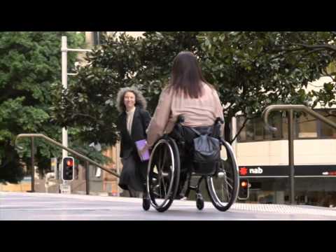 Lady in a wheelchair wheeling down the street