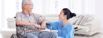 Aged care support worker crouching down to talk with a wheelchair user.