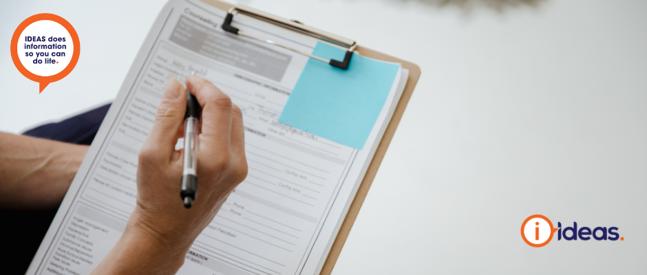 An individual holds a clipboard and pen, filling out a form.