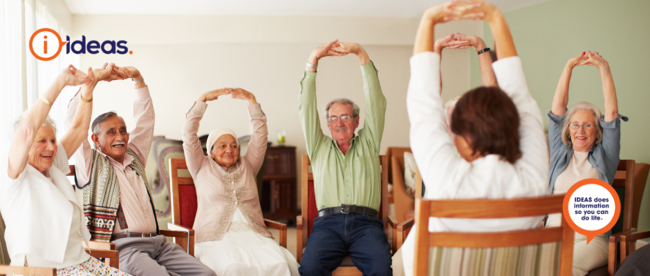 Group of elderly people in aged care sitining down, stretching their arms up