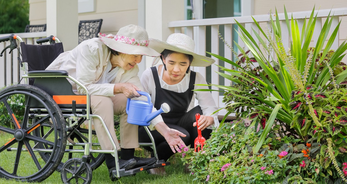 Elderly woman gardening in backyard with daughter