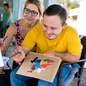 Image of man in yellow shirt smiling and painting.