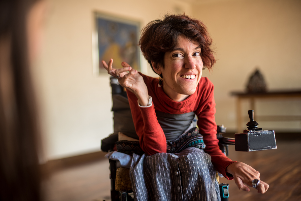 Image of woman with disability in wheelchair smiling at the camera.