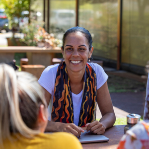 Image of woman sitting at table smiling at a friend or colleague. 