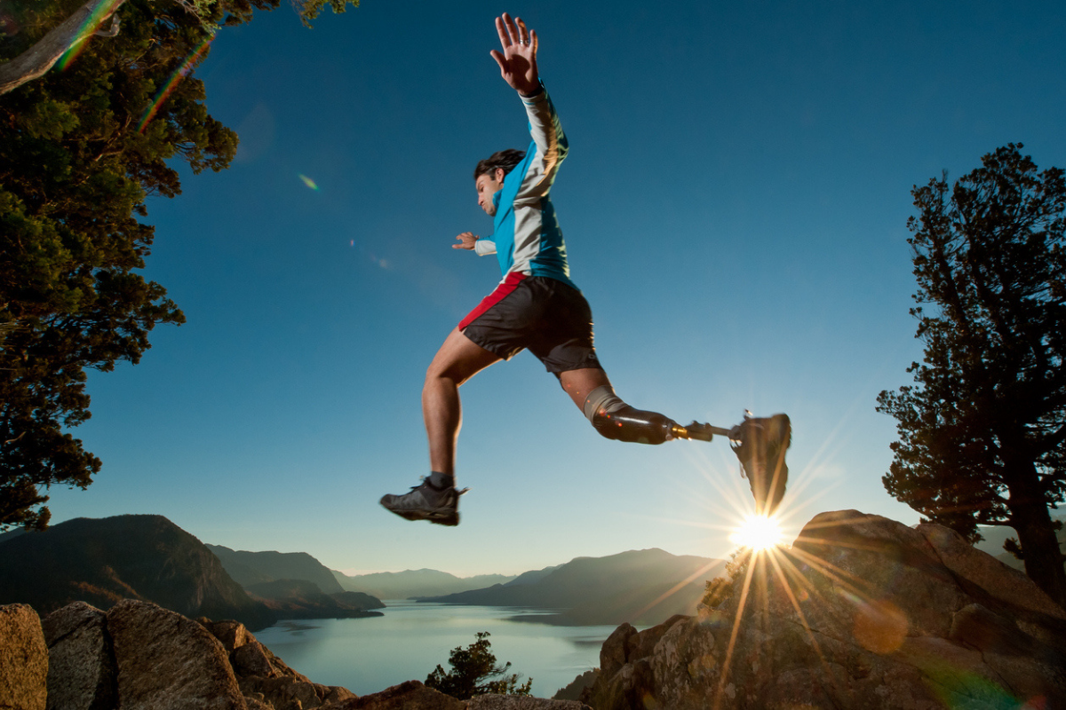 Image of man with prosthetic leg leaping from one rock to another.