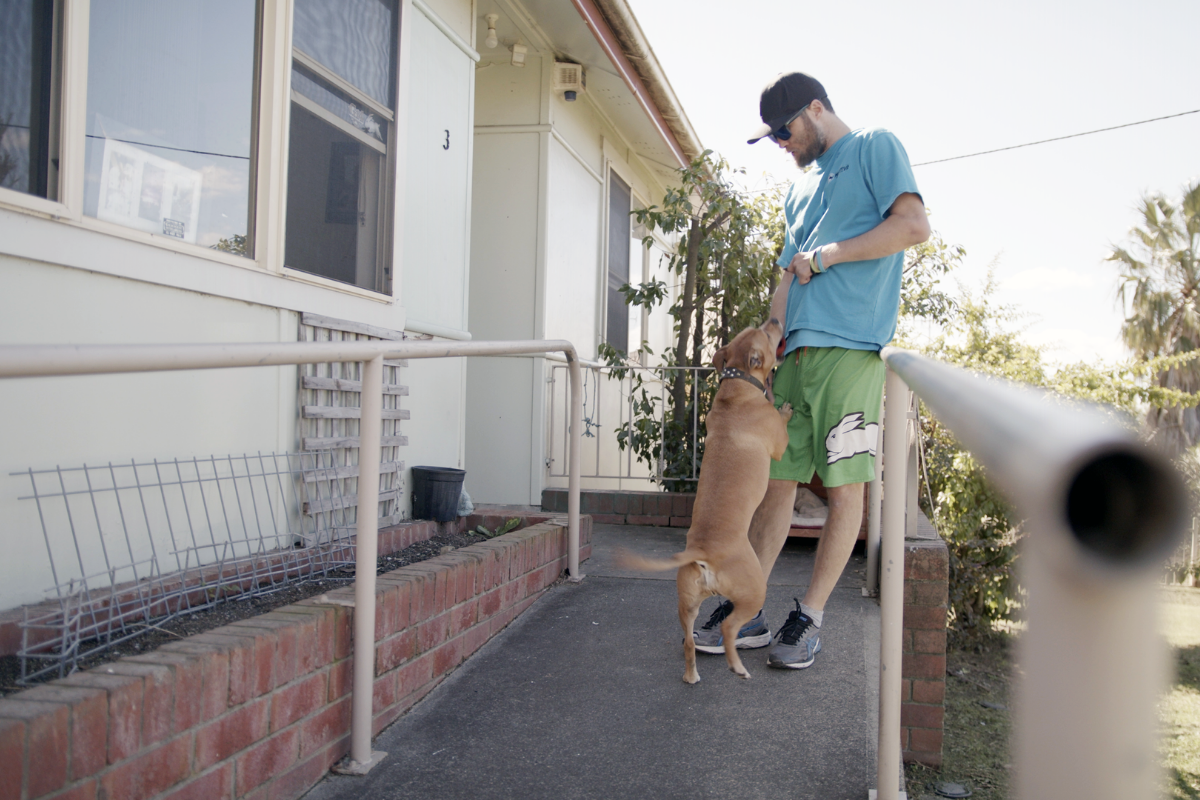 Image of man leaning on a rail playing with his dog.