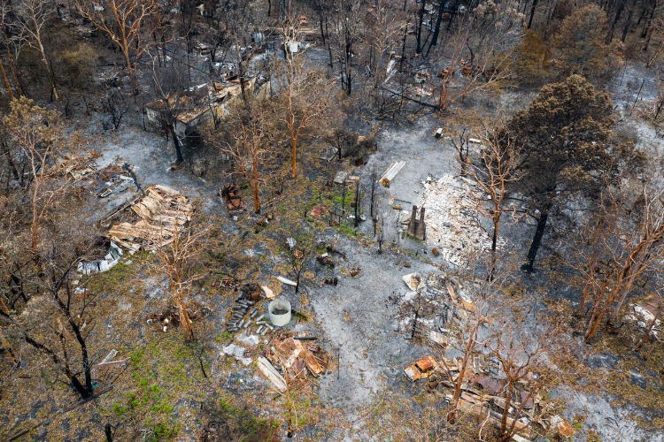 debris from a house in burnt out bush. Only the chimney is still standing. 