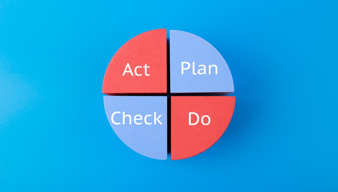 A cycle diagram with the words plan, do, act and check in white font on red and light blue quarter inscription on blue background picture.