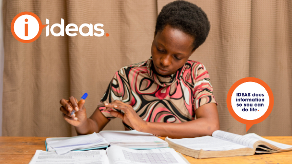 Woman sitting at desk, with pen in her hand reading 3 textbooks.