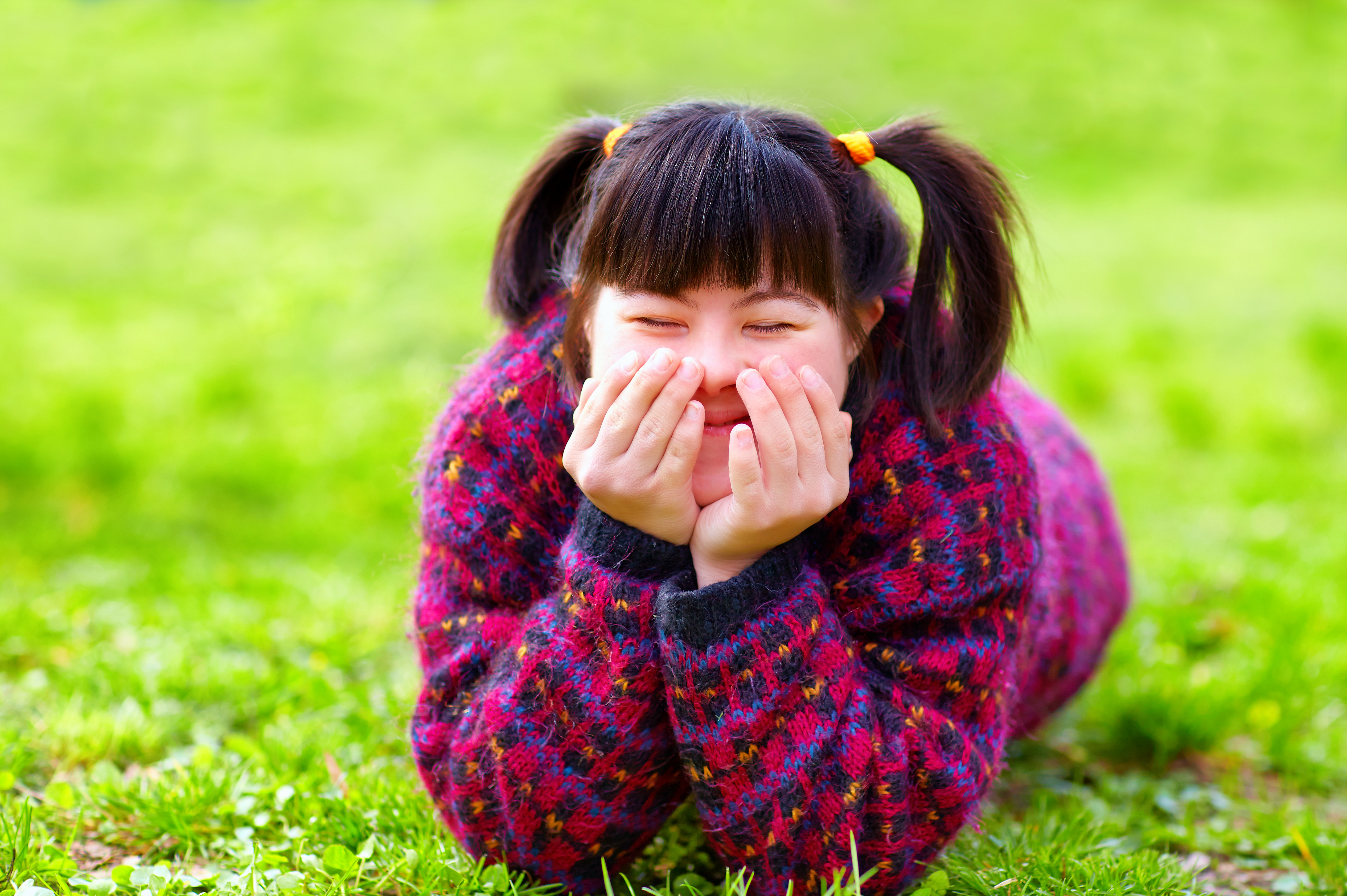 young girl with a disability lying on grass smiling 