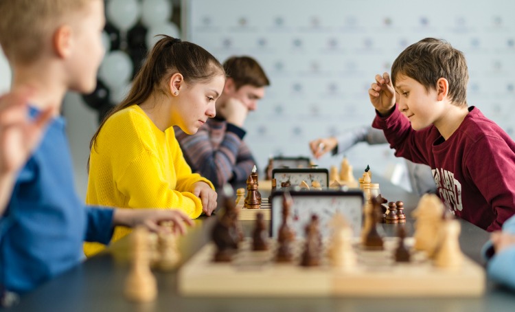 Kids of different ages boys and girls playing chess in a tournament