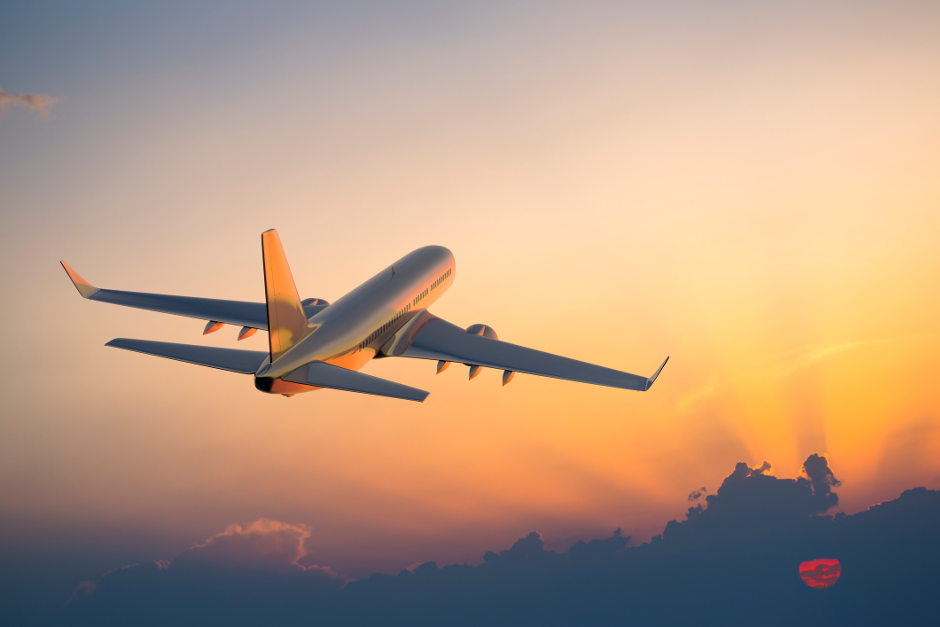 An image of a jet flying into the sunset over clouds