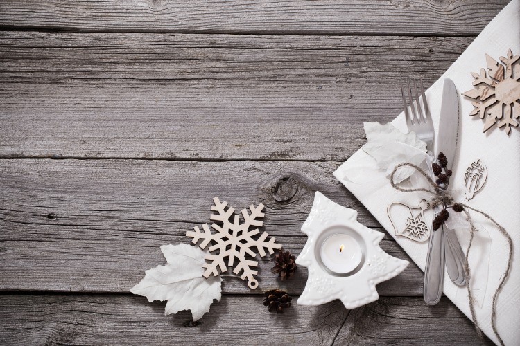 Wooden table set with a knife and fork and Christmas candle and snowflake ornament