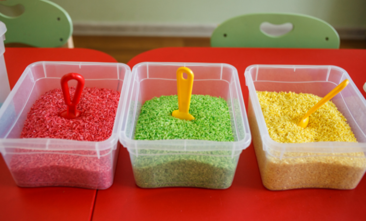 3 tubs of coloured rice, red, green and yellow.