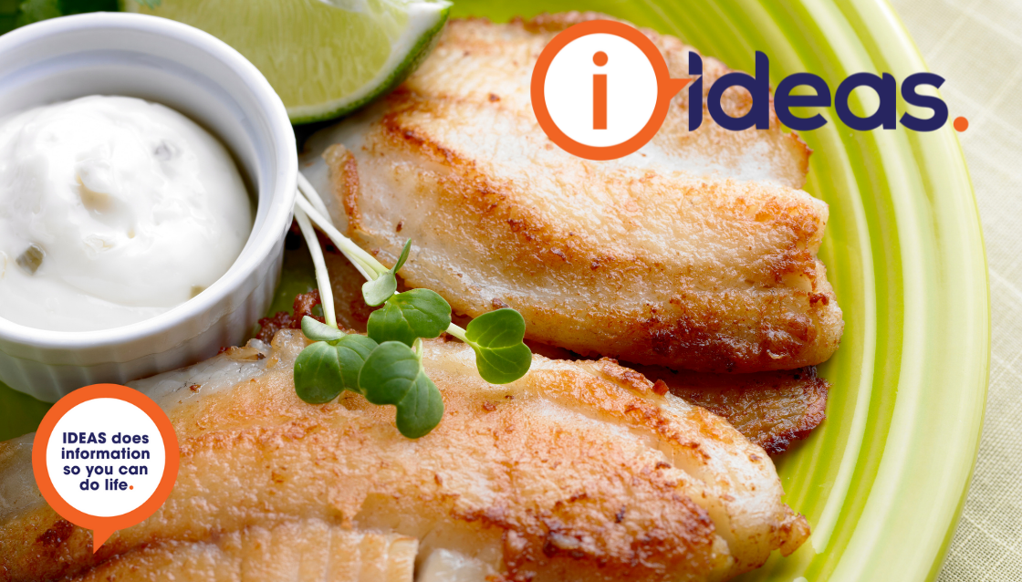 A bright green plate, with golden cooked fish, some garnish, a lime wedge and tartare sauce.
