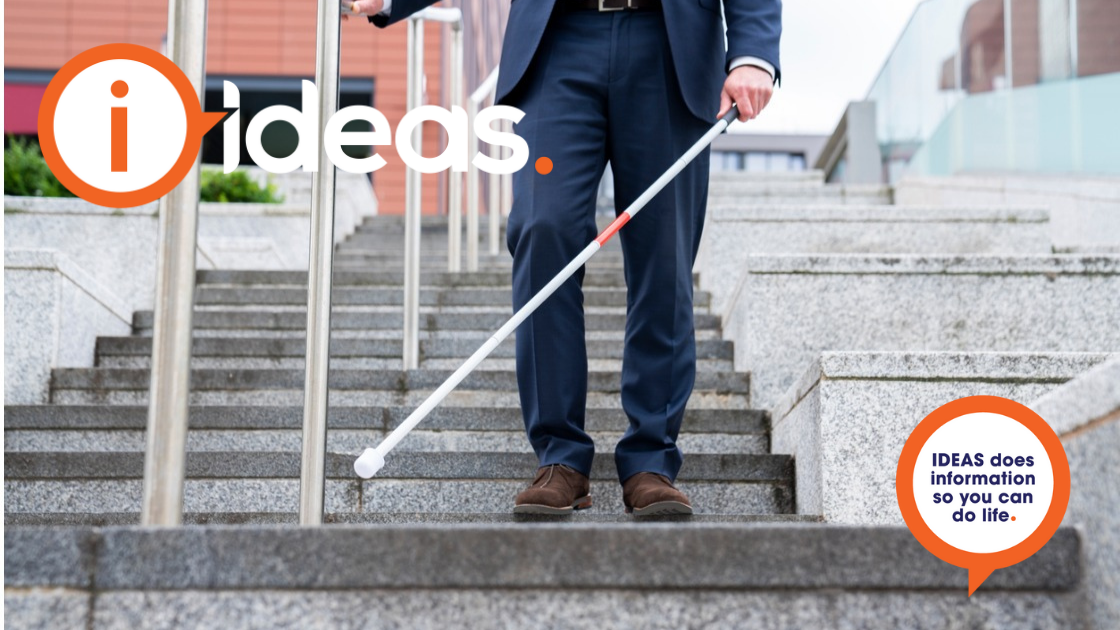 A man in dark suit navigates stairs with a cane.