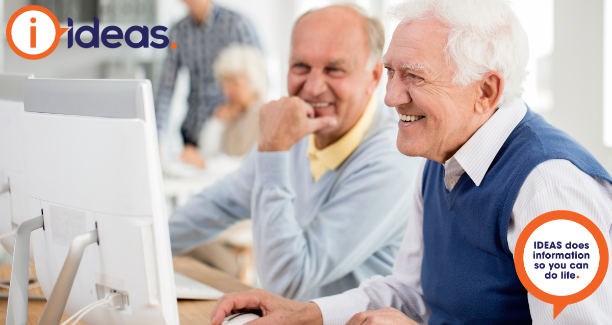 Two senior males are looking at a computer.