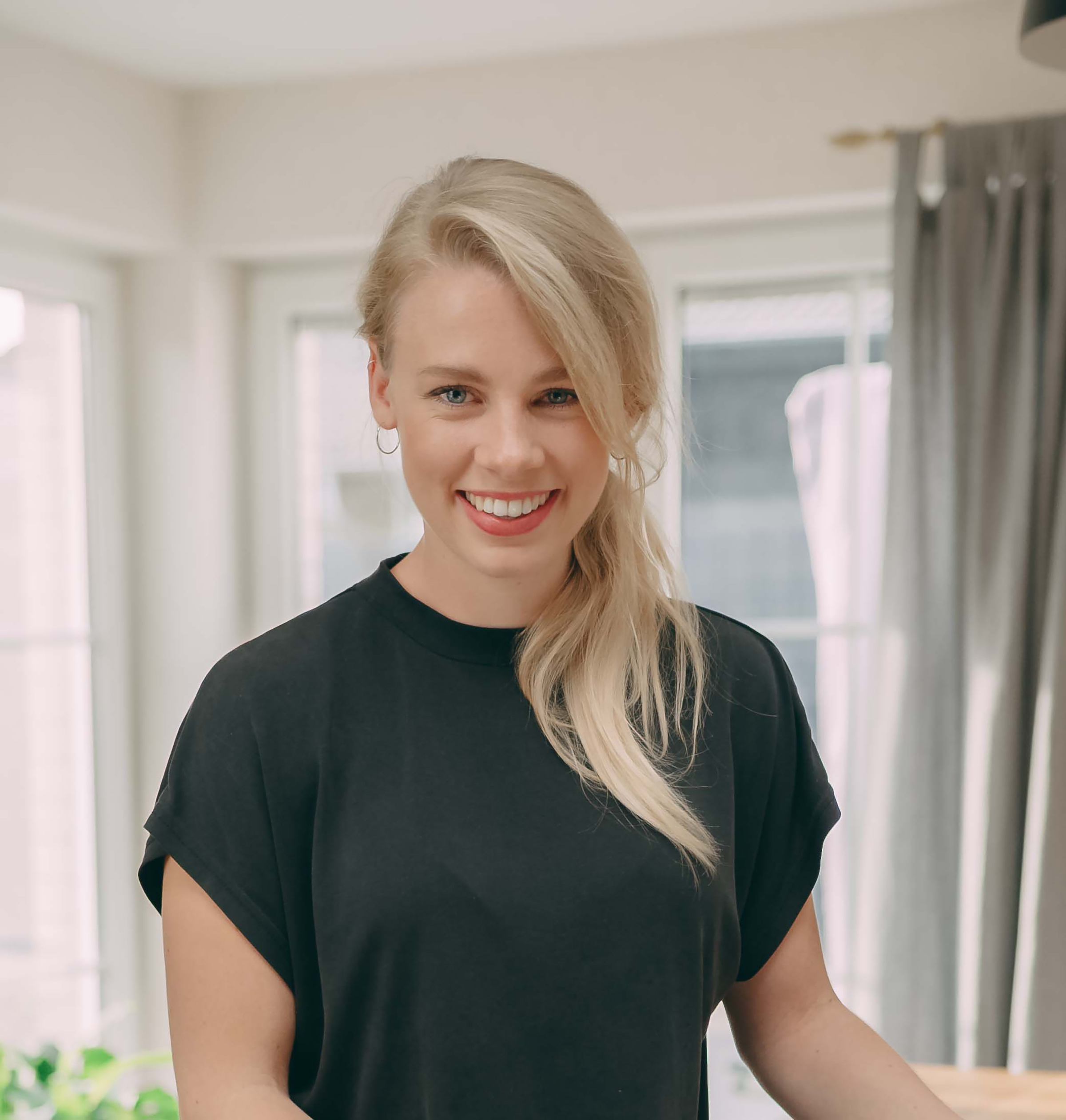 Woman with blonde ponytail and black t-shirt, smiling