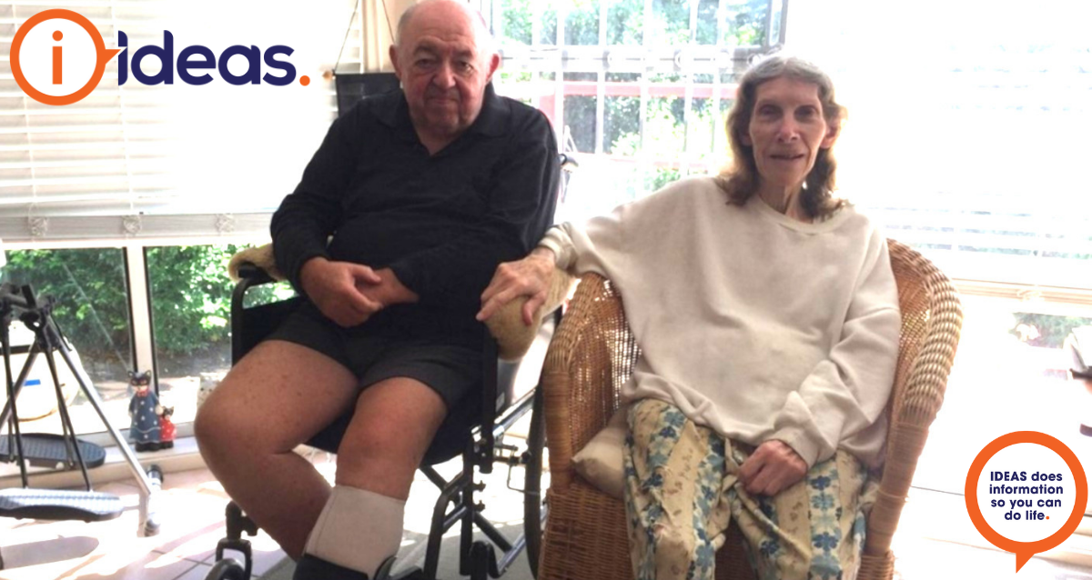 Phillip Barr in his wheelchair at home with his wife by his side.