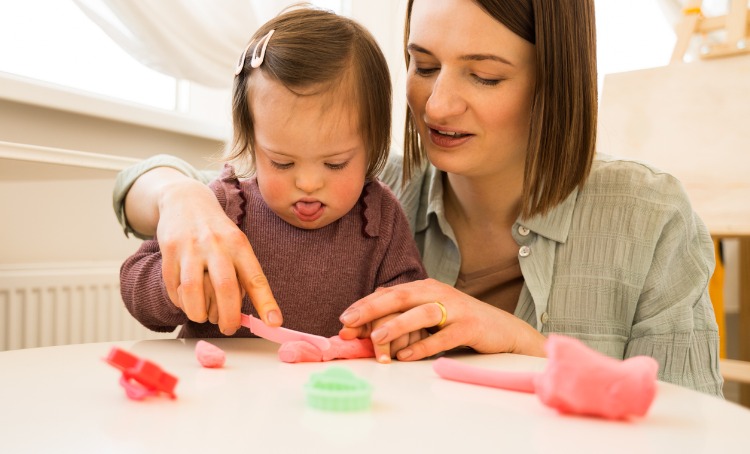 A girl and adult play with playdough