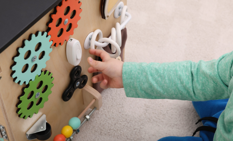 Little child playing with busy board house on floor, closeup