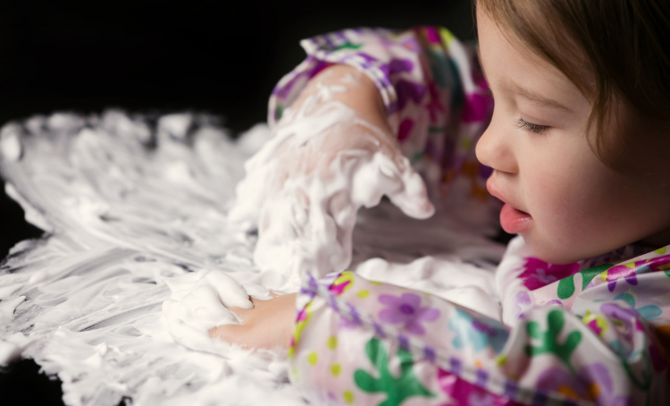 A child plays in shaving cream on the table