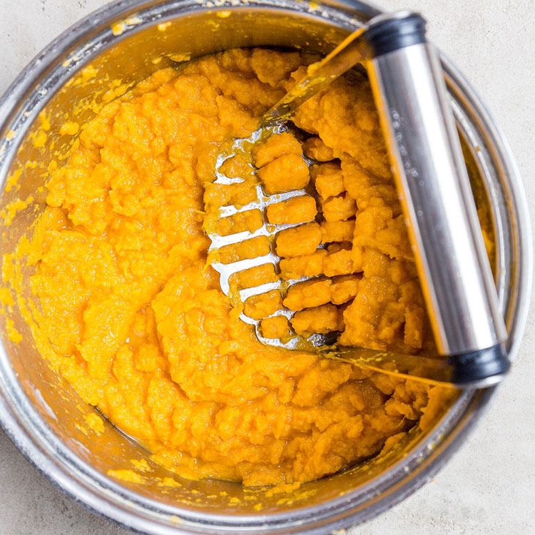 mashed sweet potato with a mashing utensil