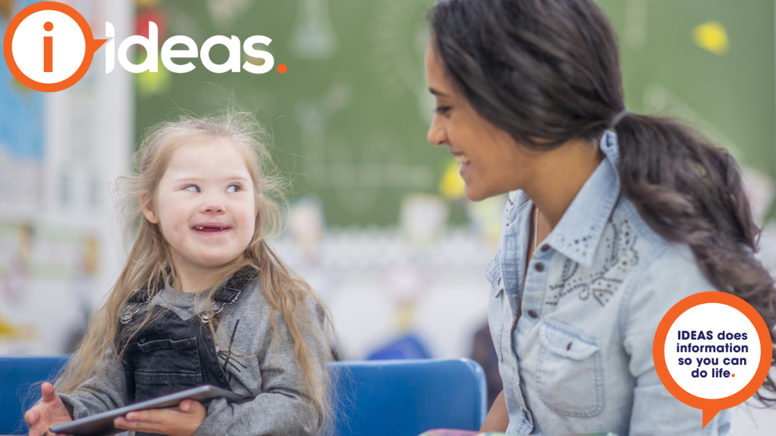 A young girl with disability and her teacher share a smile.