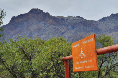 wheelchair accessible walking track sign with mountain peak behind