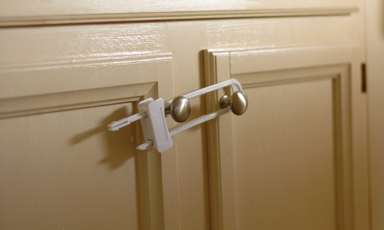 Close up image of a child lock around two cupboard handles.