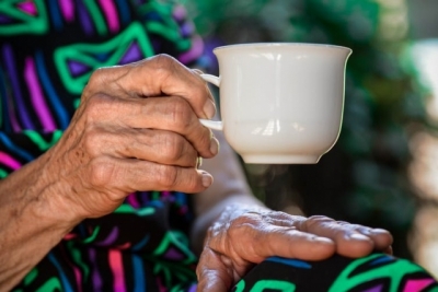 Image of an aged woman's hand holding a white cup