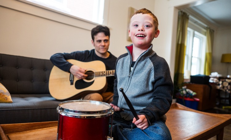 boy with down syndrome playing music with dad 