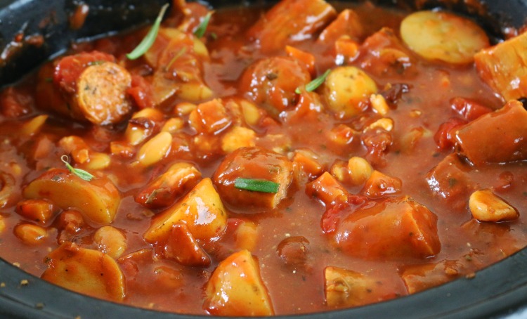 A photo of homemade casserole, with sausages and vegetables, cooking in a pot.