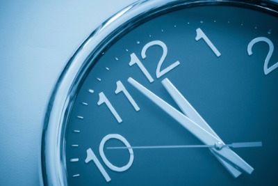 Image of analog clock face with hands approaching the stroke of 12.