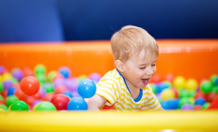 little boy playing in ball pit