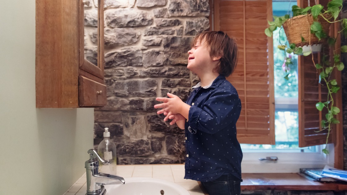 little boy with down syndrome washing his hands picture id1044326908