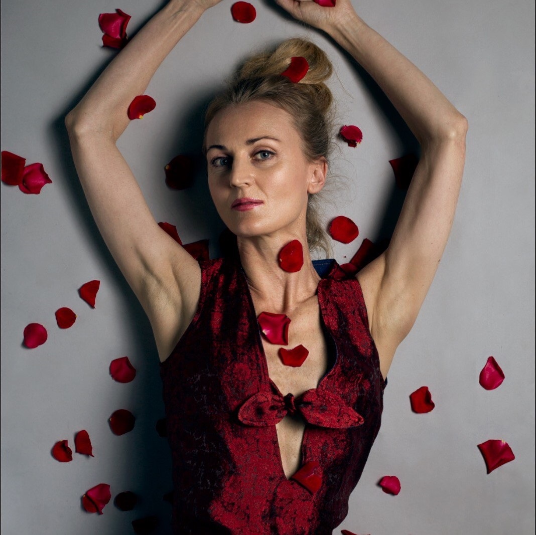 Nikki Hind. Blonde woman wearing a fitted red dress with rose petals.