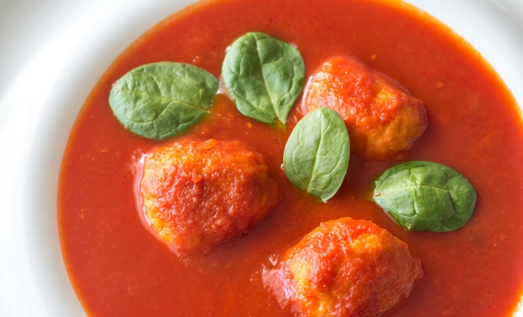 portion of tomato soup with meatballs picture. Basil sprinkled in the soup.