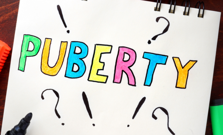 The word "Puberty" written in colourful capital letters, and around it are question marks and exclamation marks.