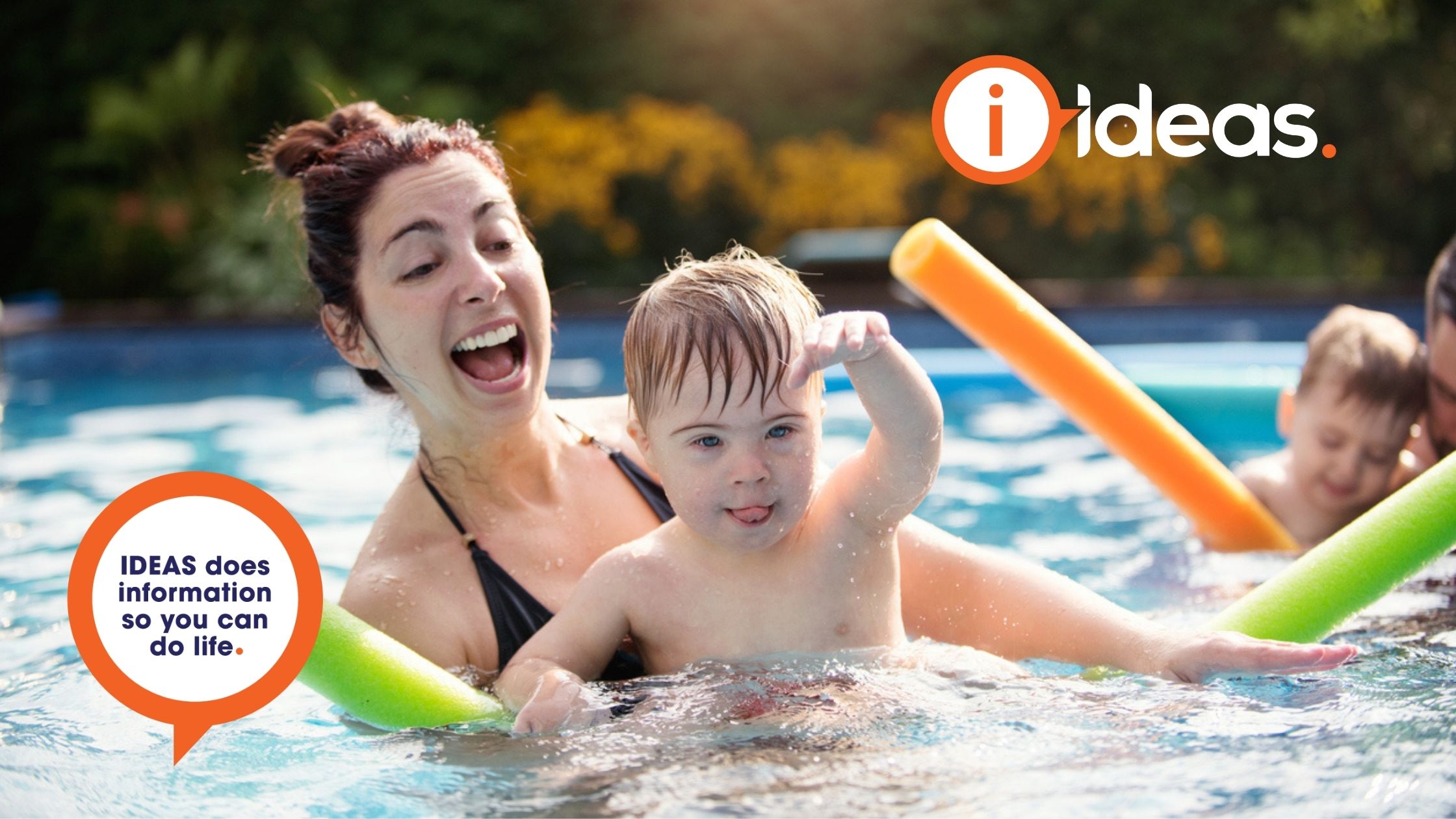 The photograph showoman and small child playing in a swimming poolws the edge of a swimming pool. There are two people, one a young girl with disability, the other a woman. The woman is holding a pool noodle in one hand, and guiding the girl into the pool with the other. They are next to a diving board with a cone placed on top.