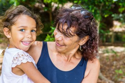 Image of smiling Aboriginal woman holding a young child in her arms.