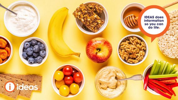 A range of healthy snacks. Banana, apple, youghurt, blueberries, honey, nuts, crackers, veggie sticks, hummus, rice cakes