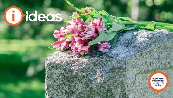 An image of a headstone with pink flowers laid in respect. 