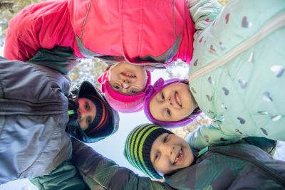 Children, one with disability, in a circle looking down at the camera.