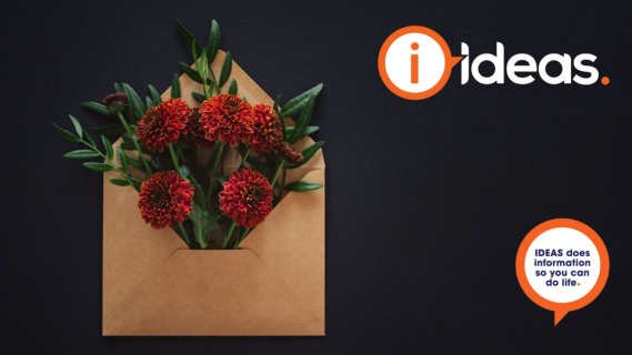 A black background with kraft envelop and redish orange flowers peeking from the envelope. Symbolising "Hope in the mail".