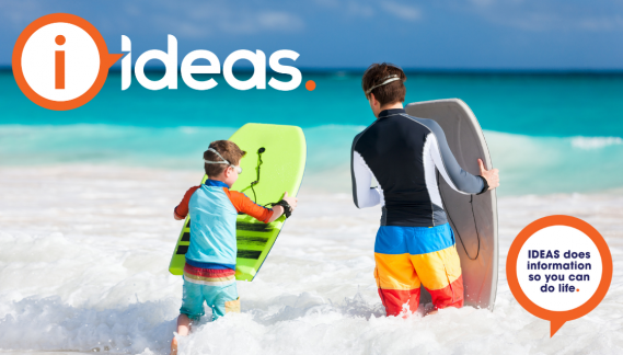 Two boys with boogie boards in the surf at the beach on a bright day.