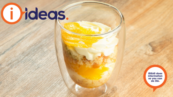 A glass with yellow toned trifle in an individual serve.