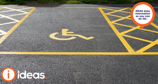 An image of a disability parking space. Within the space is a yellow painted symbol of person in a wheelchair. Beside the parking space are two areas with cross marks to illustrate clear space on each side of the parking space.