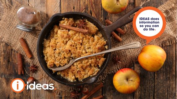 a cast iron skillet filled with crumble. applies, cinamon sticks and star anise arranged around it. 