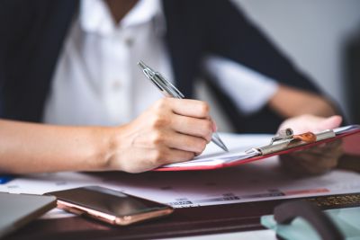 Close up photo of females hand holding a pen and filling out a form.